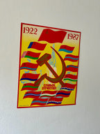 Poster with a rocket, hammer and sickle symbol and text on a yellow background, featuring the years 1922 and 1987.