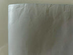 Close-up of a white sheet with visible texture and folds on a beige background