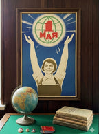 Framed poster with a woman holding up a number one symbol, surrounded by books and a globe on a table.
