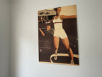Vintage-style poster of a woman in athletic wear on a plain wall.