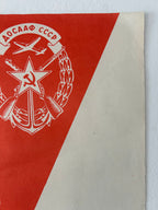 Red and beige paper with a white emblem featuring a star, hammer, and sickle on a white background