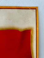 Framed artwork with a red center and wooden frame on a light blue wall.