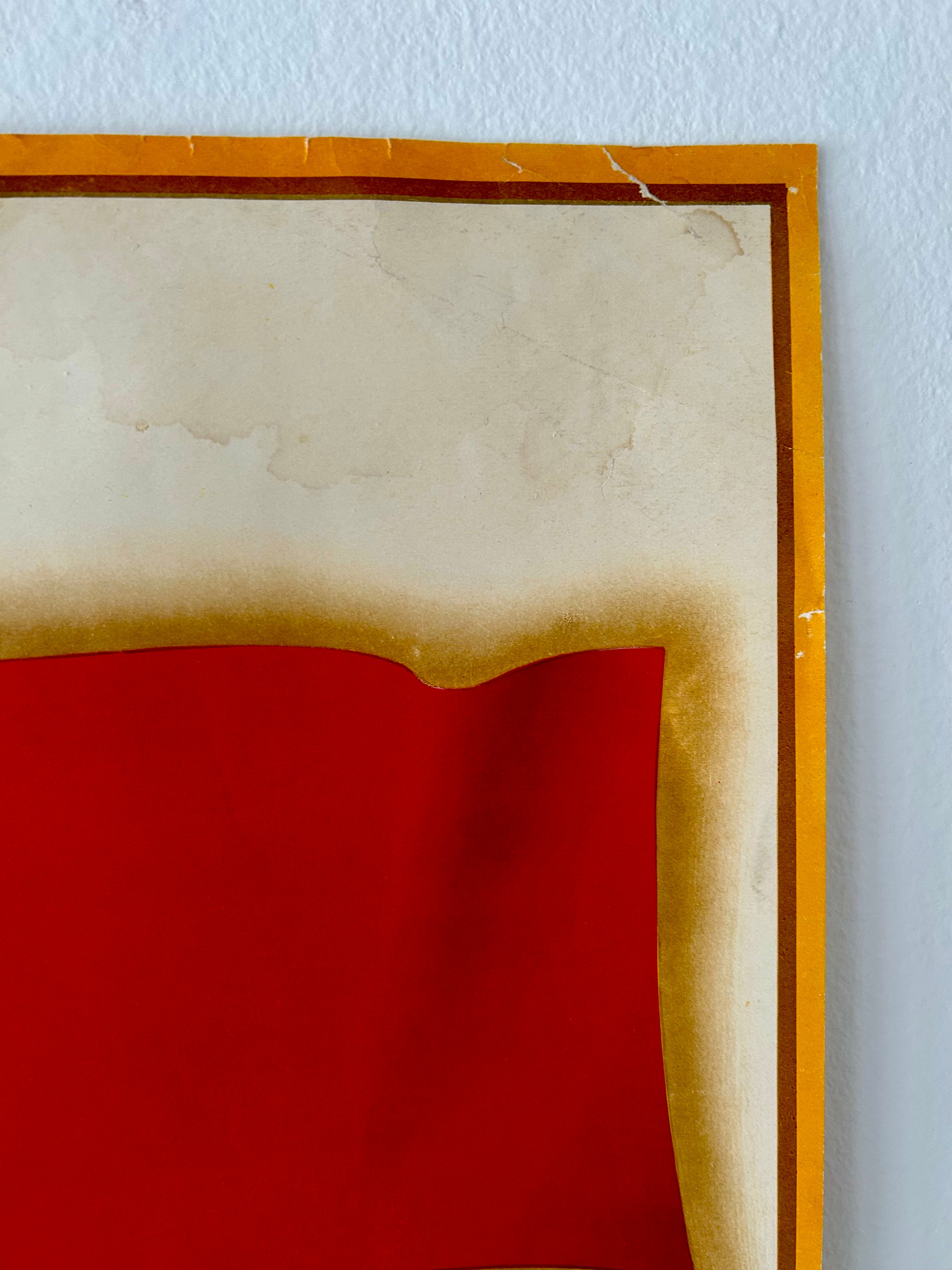 Framed artwork with a red center and wooden frame on a light blue wall.