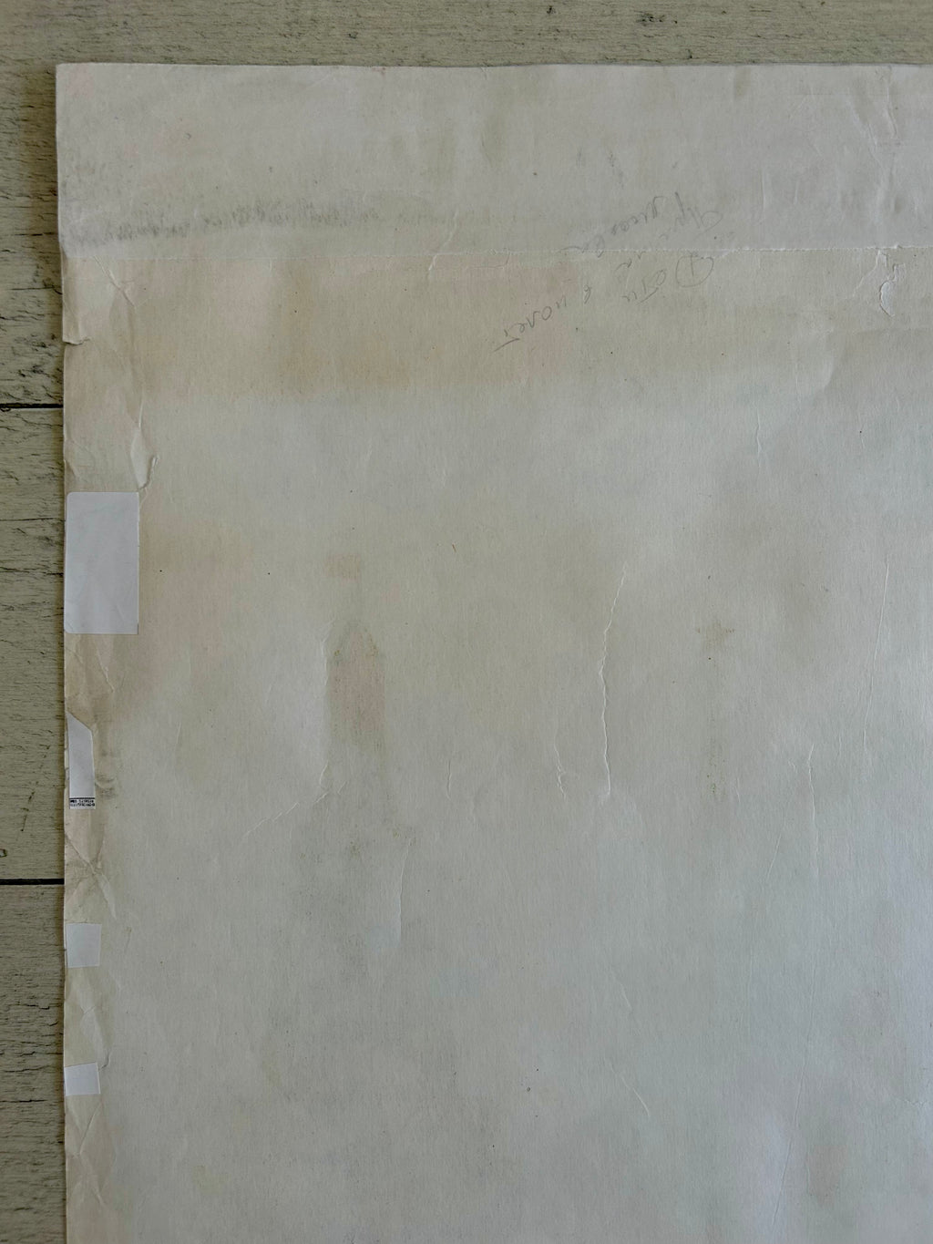 Sheet of beige paper with visible wear and tear on a wooden surface