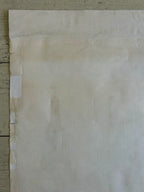 Sheet of beige paper with visible wear and tear on a wooden surface