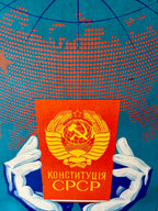 Book titled 'Конституция СССР' held by hands against a world map background