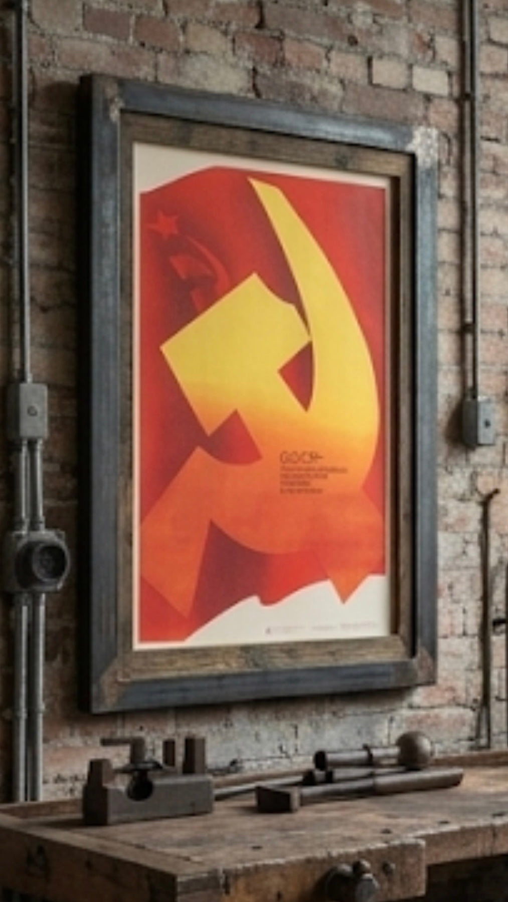 Framed poster with a red and yellow design on a brick wall with tools below.