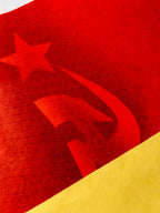 Close-up of a flag with a red star and hammer-sickle symbol on a red and yellow background