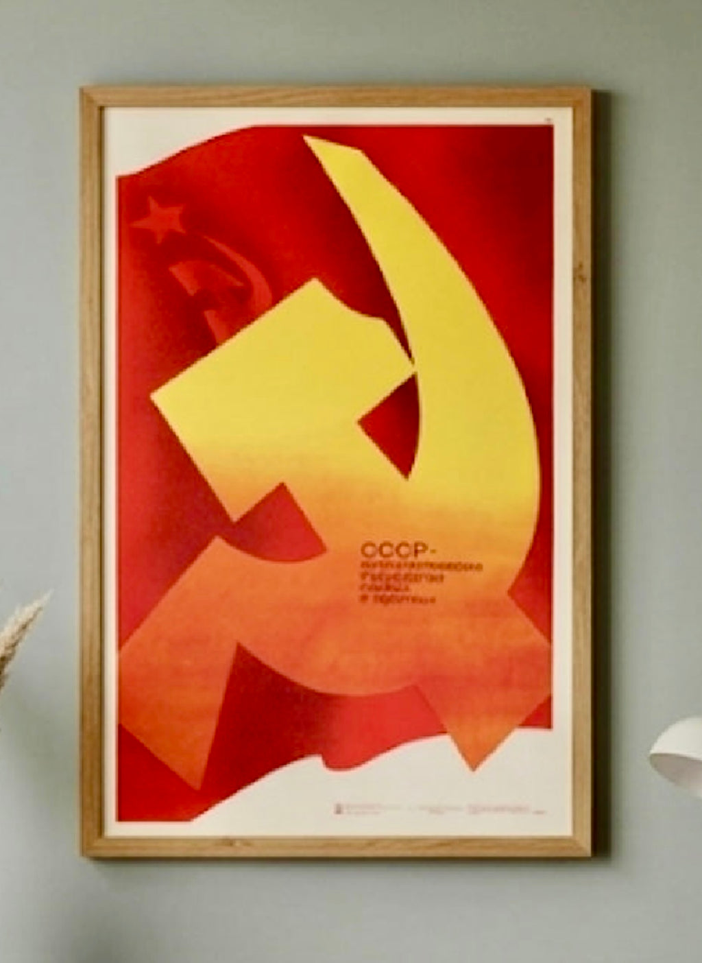 Framed poster with a yellow hammer and sickle symbol on a red background, featuring 'CCCP' text.