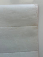 Close-up of a textured white paper with a slight brown discoloration.