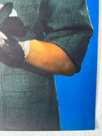 Person wearing a dark coat with a blue background