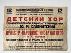A vintage Russian concert poster for a children's chorus and orchestra performance, printed on aged beige paper with red and black text, photographed against a white wall.