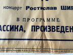 A close-up of a vintage beige paper program cover printed with dark blue Cyrillic text, showing part of a concert program title and performer names.
