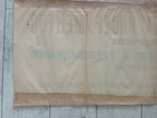 A vintage beige paper banner or sign with faded Cyrillic text, laid flat on a light-colored wooden surface.