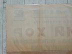 A vintage beige paper label or packaging sheet with faded Cyrillic text, laid flat on a light gray wood plank surface.