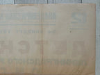 A vintage beige paper document or poster with faded Cyrillic text, laid flat on a light gray wooden surface.
