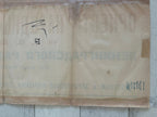 A vintage beige paper envelope or document with faded blue Cyrillic text and a black handwritten mark, laid flat on a light wood surface.