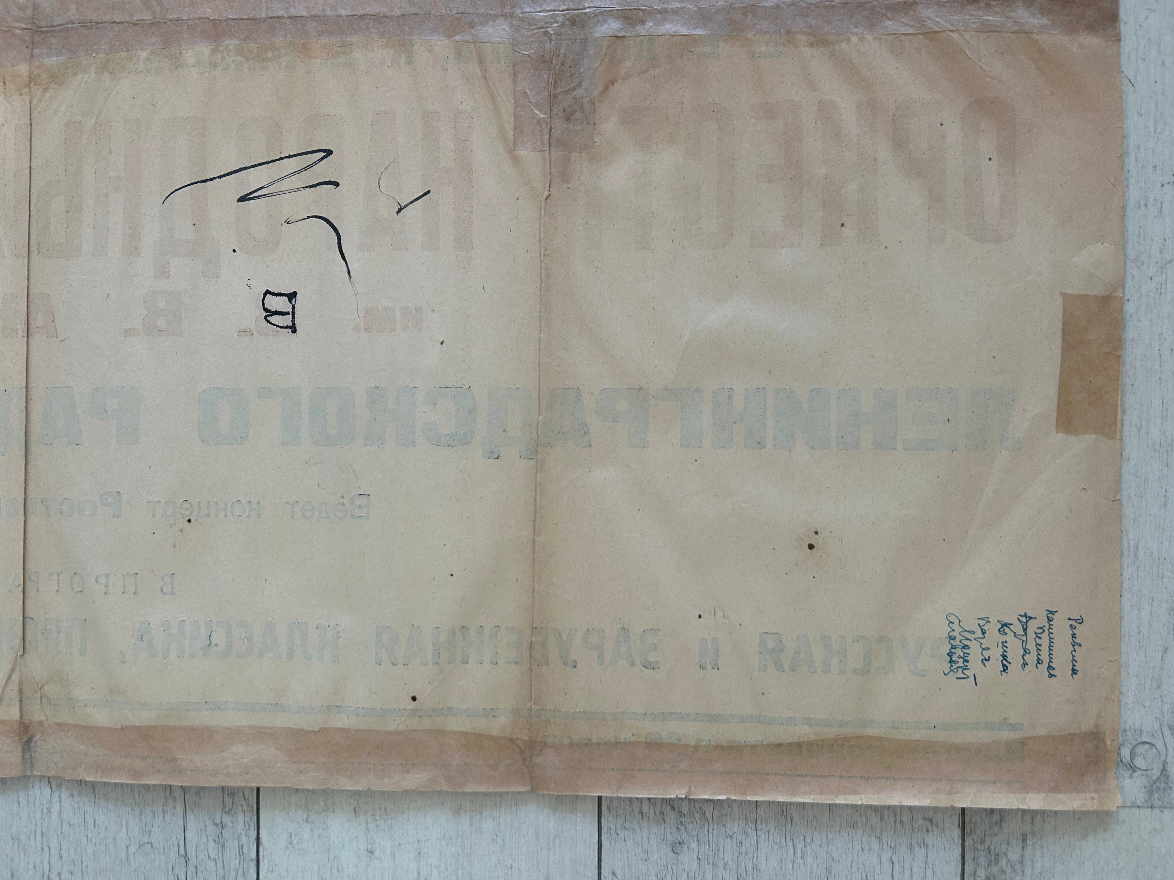 A vintage beige paper envelope or document with faded blue Cyrillic text and a black handwritten mark, laid flat on a light wood surface.