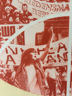 A close-up of a circular printed graphic or sticker featuring a sepia-toned protest scene with banners and text, including the word 'Beating' and other partially visible words.