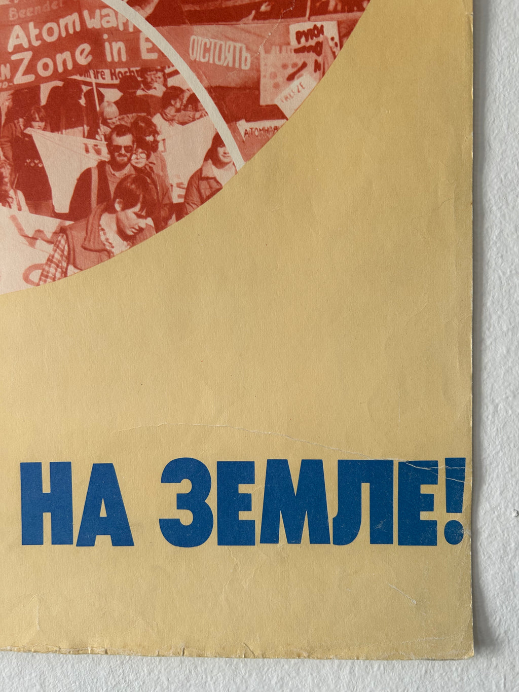 A close-up of a vintage paper item, likely a flyer, poster, or booklet page, featuring bold blue Cyrillic text on a beige background with a red-toned circular collage on the left.