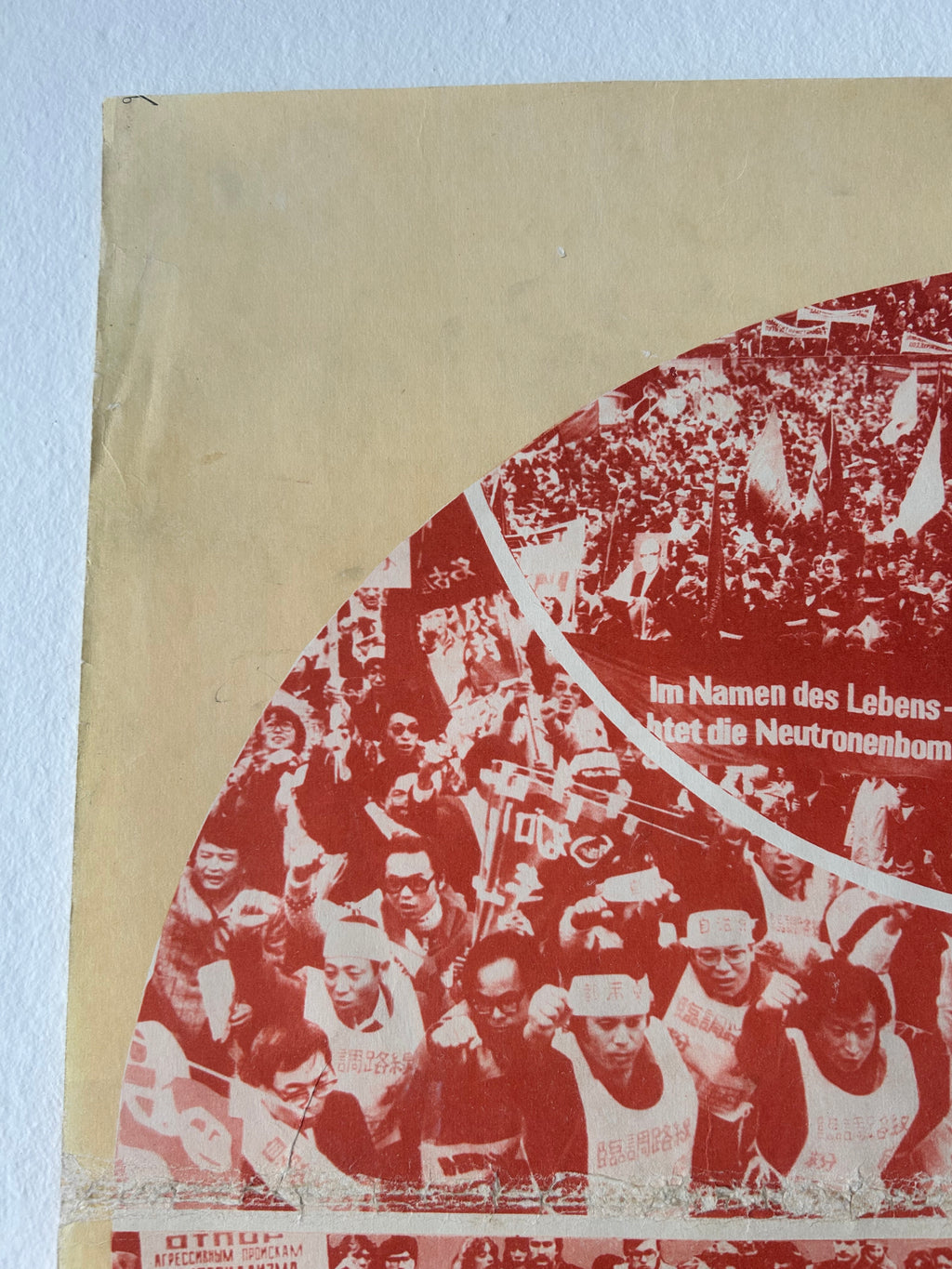 A close-up of a vintage printed poster or booklet page with a cream-colored border and a red printed collage of people, including visible German text.