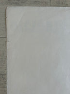 A large blank white sheet of paper or cardstock laid flat on a light gray wood-grain surface.