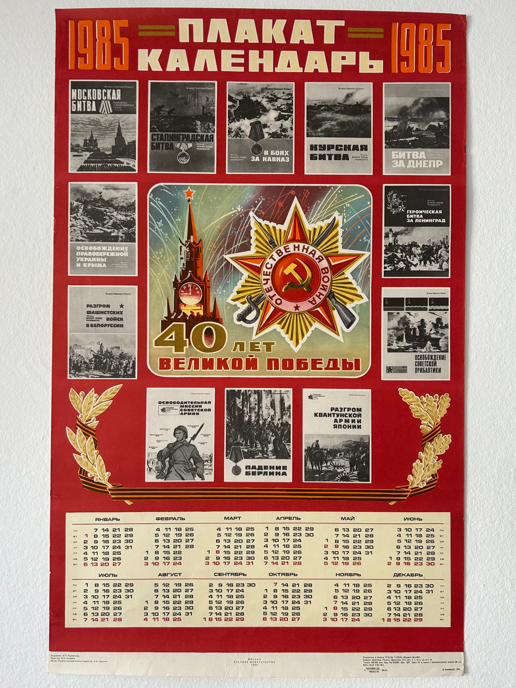 A vintage Soviet calendar poster from 1985 commemorating 40 years of victory, featuring a red border, historical black-and-white photos, a central gold and red military medal emblem, and a cream-colored calendar grid at the bottom.