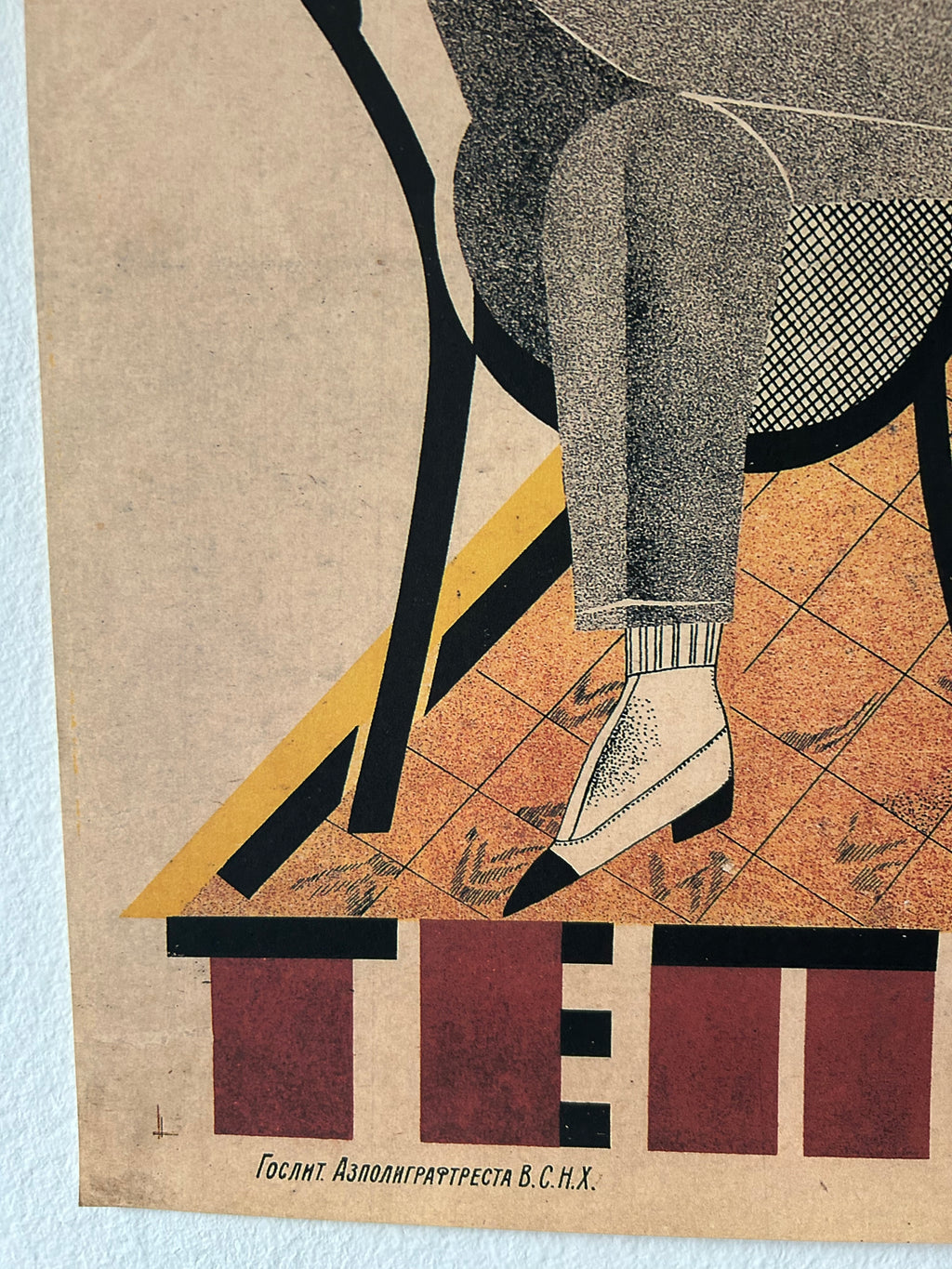 A vintage-style poster print featuring an abstract illustration of a seated figure in gray trousers and white shoes, with bold black, yellow, and terracotta geometric shapes on a tan background. The bottom includes large red and black letterforms and small Cyrillic text.
