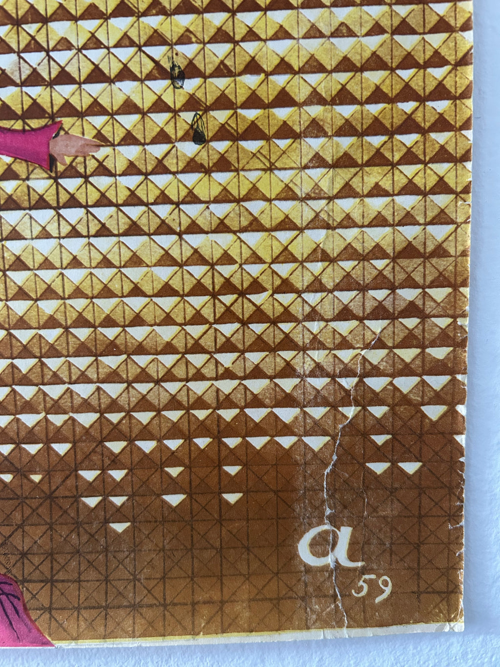 A close-up of a vintage postage stamp featuring a brown and gold geometric triangle pattern, with a white handwritten 'a 59' on the right side and a small pink illustration at the bottom.