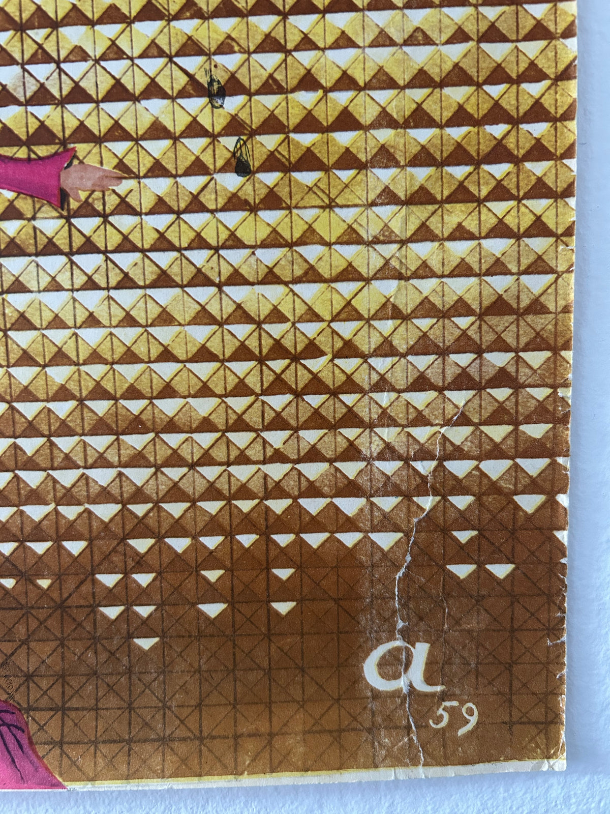 A close-up of a vintage postage stamp featuring a brown and gold geometric triangle pattern, with a white handwritten 'a 59' on the right side and a small pink illustration at the bottom.