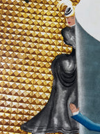 A close-up of a decorative surface featuring a repeating gold and brown geometric triangle pattern, overlaid with a large dark gray draped fabric and a partial blue garment with a visible hand.