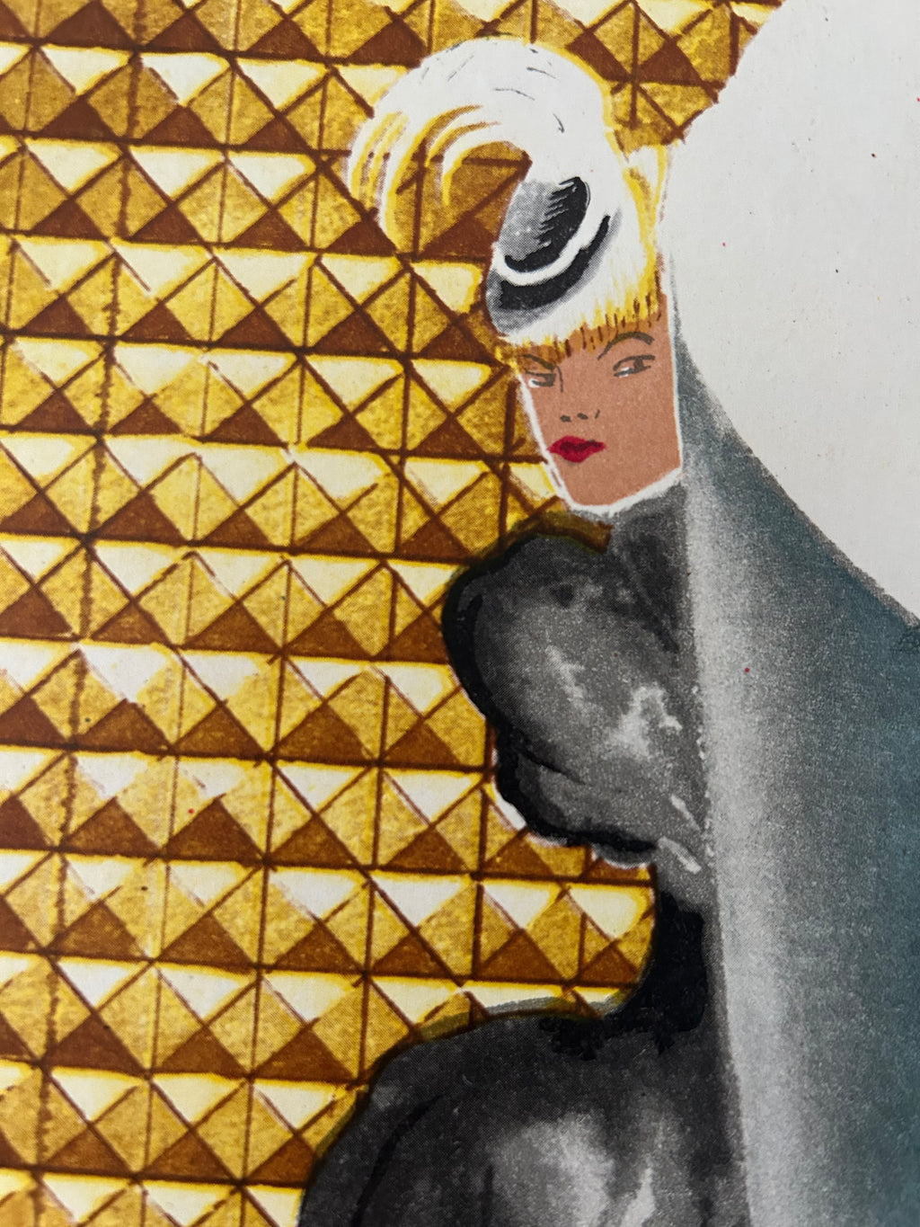 Close-up of a patterned surface with a repeating gold and brown geometric triangle design, overlaid by a dark gray curved shape and a small illustrated face detail.