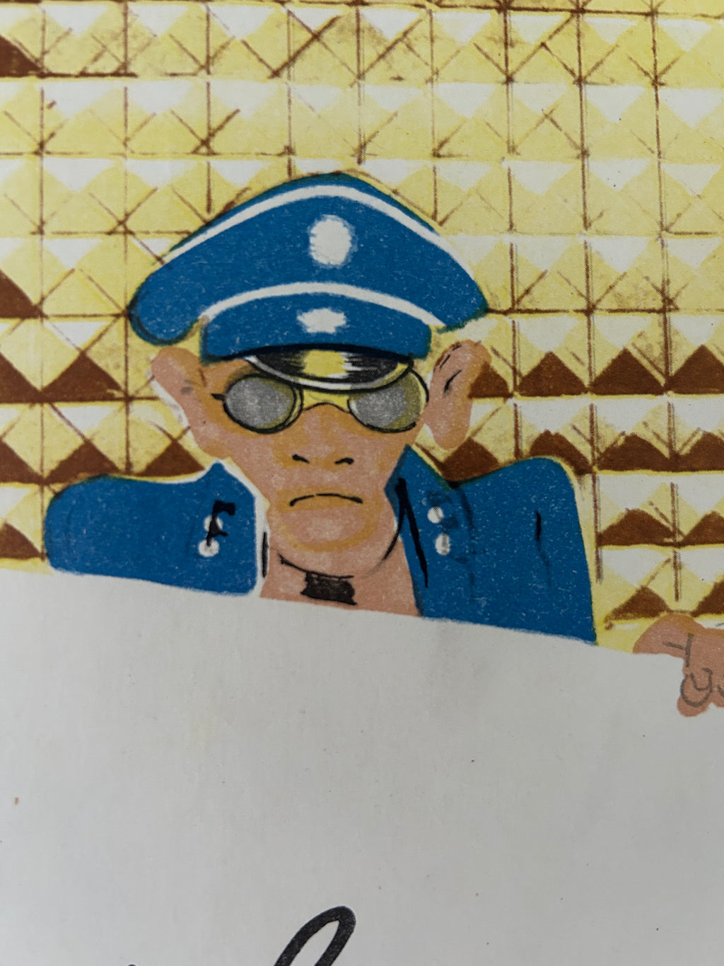 A close-up of a printed illustration showing a cartoon police officer in a blue uniform and hat, with a yellow geometric patterned background and part of a white surface visible on the right.