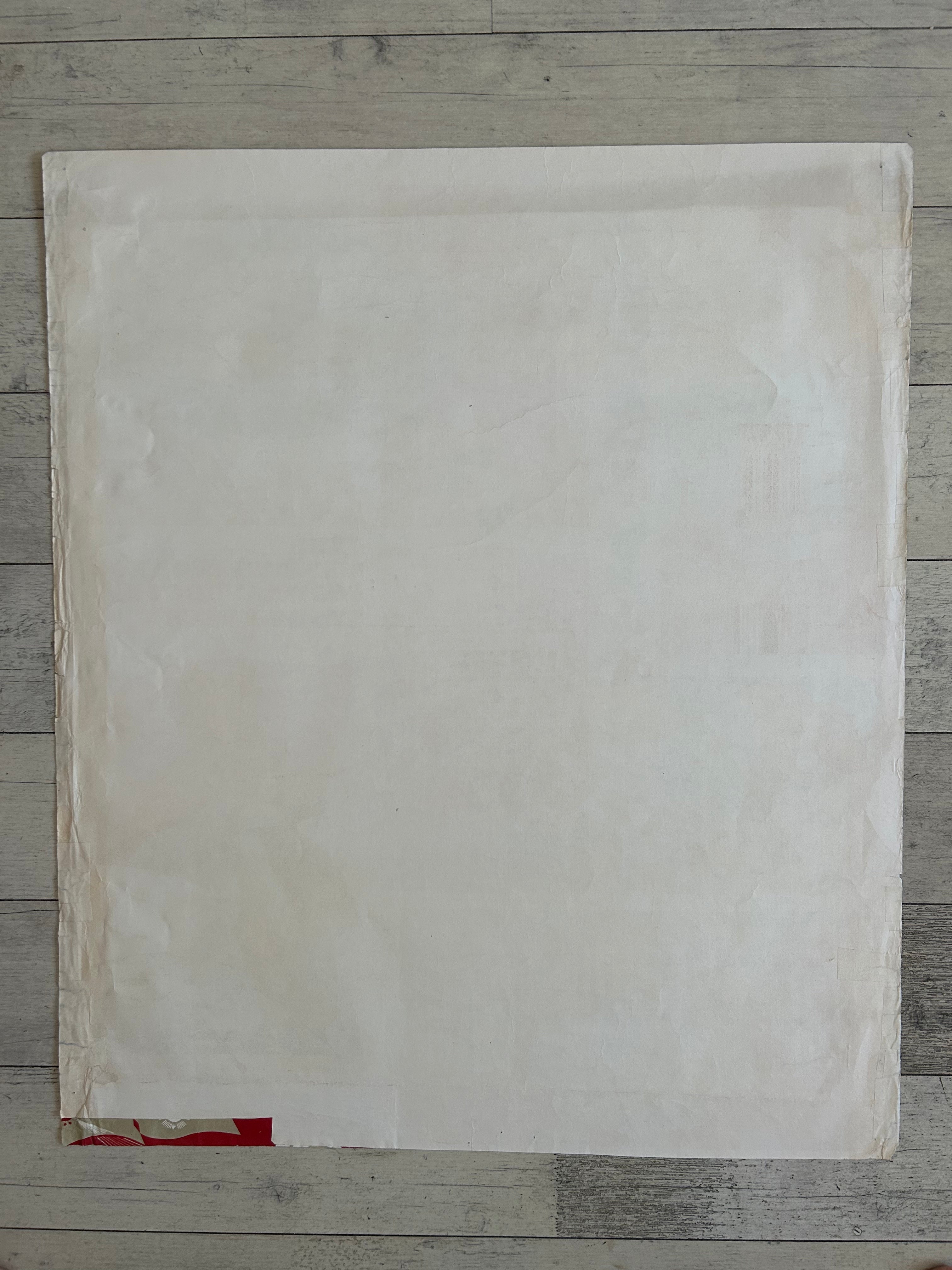 A large, blank off-white sheet of paper or cardstock laid flat on a gray wooden plank surface.
