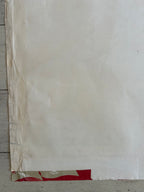 A close-up of a large off-white sheet or panel with visible wrinkles, covering most of the frame, with a small red and beige patterned section visible along the right edge.