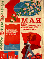 A vintage Soviet-style propaganda poster print with bold red typography, a blue globe, pink blossoms, and a figure carrying a red flag on a cream background.