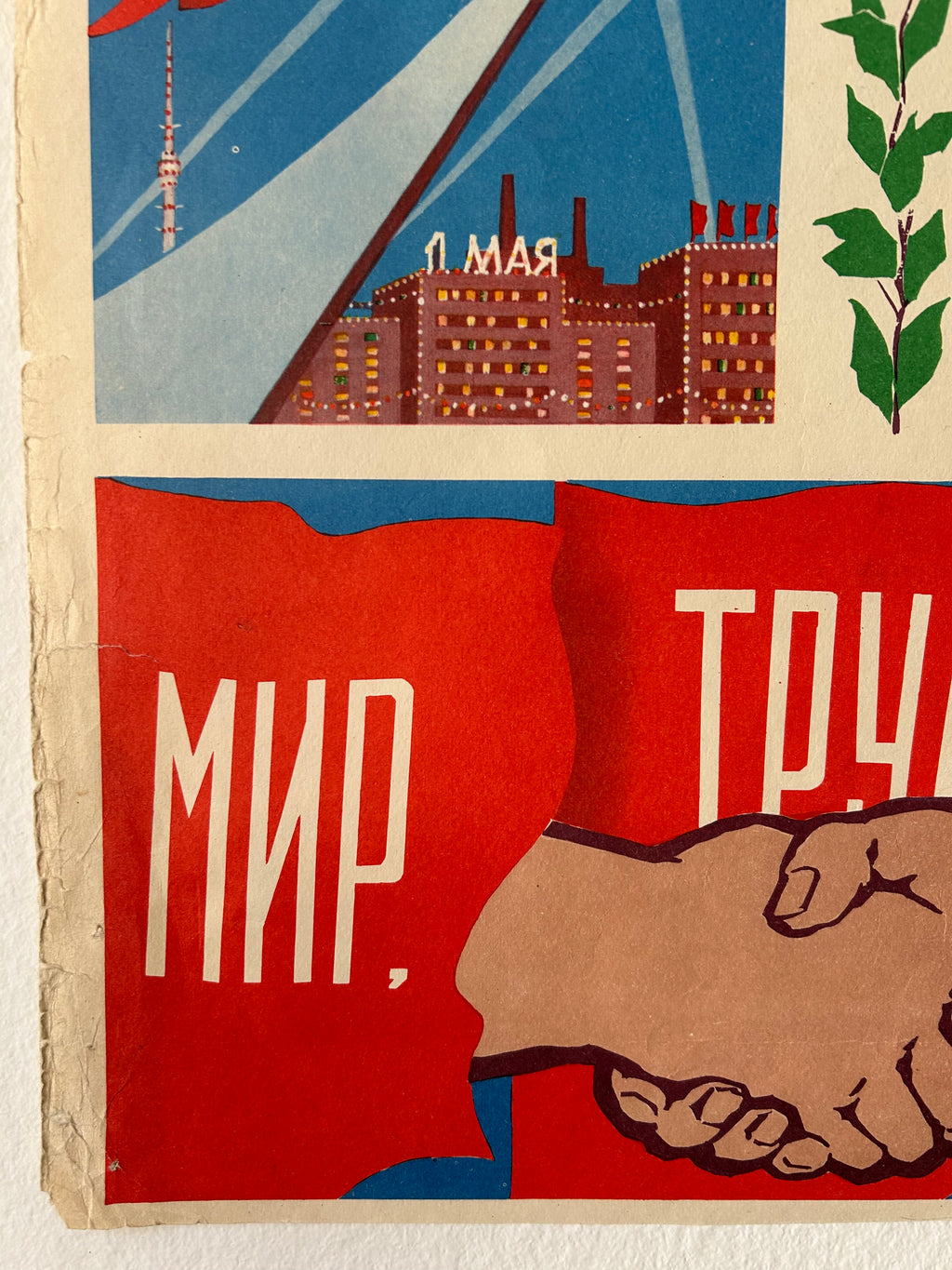 A close-up of a vintage Soviet propaganda poster print featuring a handshake, a cityscape with the word 'Leningrad', and large Cyrillic text on red and blue panels.
