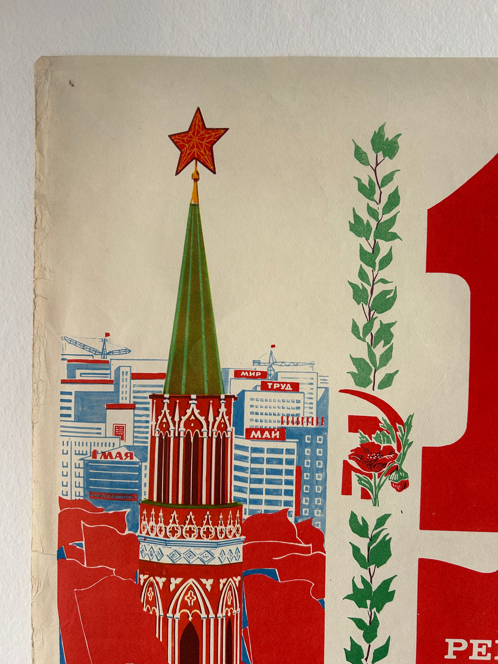 A vintage-style illustrated print or poster showing a red and cream background with a green wreath, a red rose, and stylized buildings and architectural forms in red, blue, white, and green.