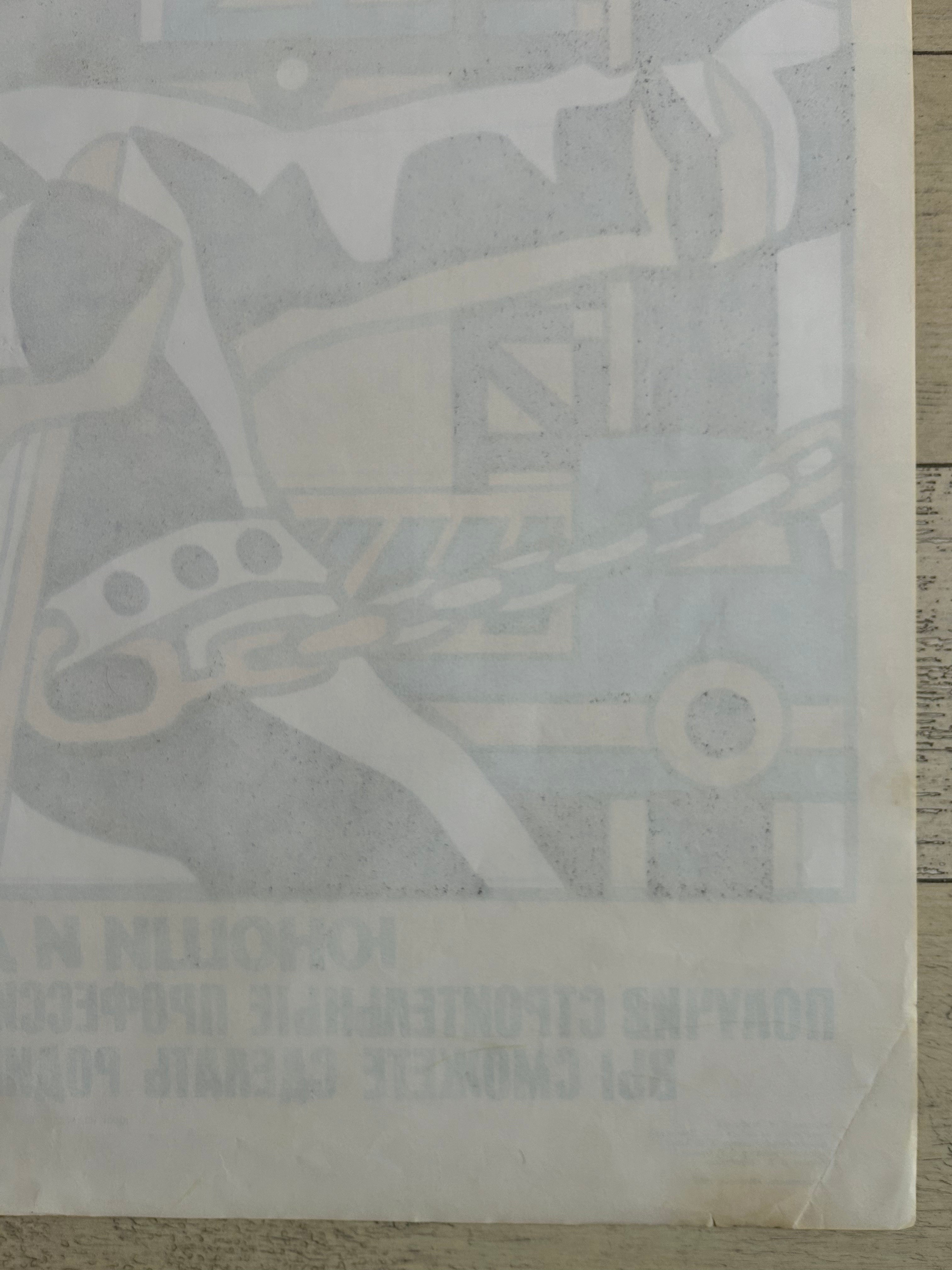 A vintage Soviet propaganda poster depicting a construction scene with a hammer and chain, printed in muted blue-gray and beige tones on aged off-white paper, laid flat on a light wood surface.