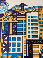A close-up of a colorful graphic print featuring stylized skyscrapers, construction cranes, and blue wave-like shapes, with a circular logo in the upper left that reads "ITO" and "Volkovskiy Sports Complex".