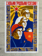 A vintage Soviet propaganda poster print featuring three workers with red stars, hats, and flags, bordered by blue and gold patterns, displayed on a light gray wood background.