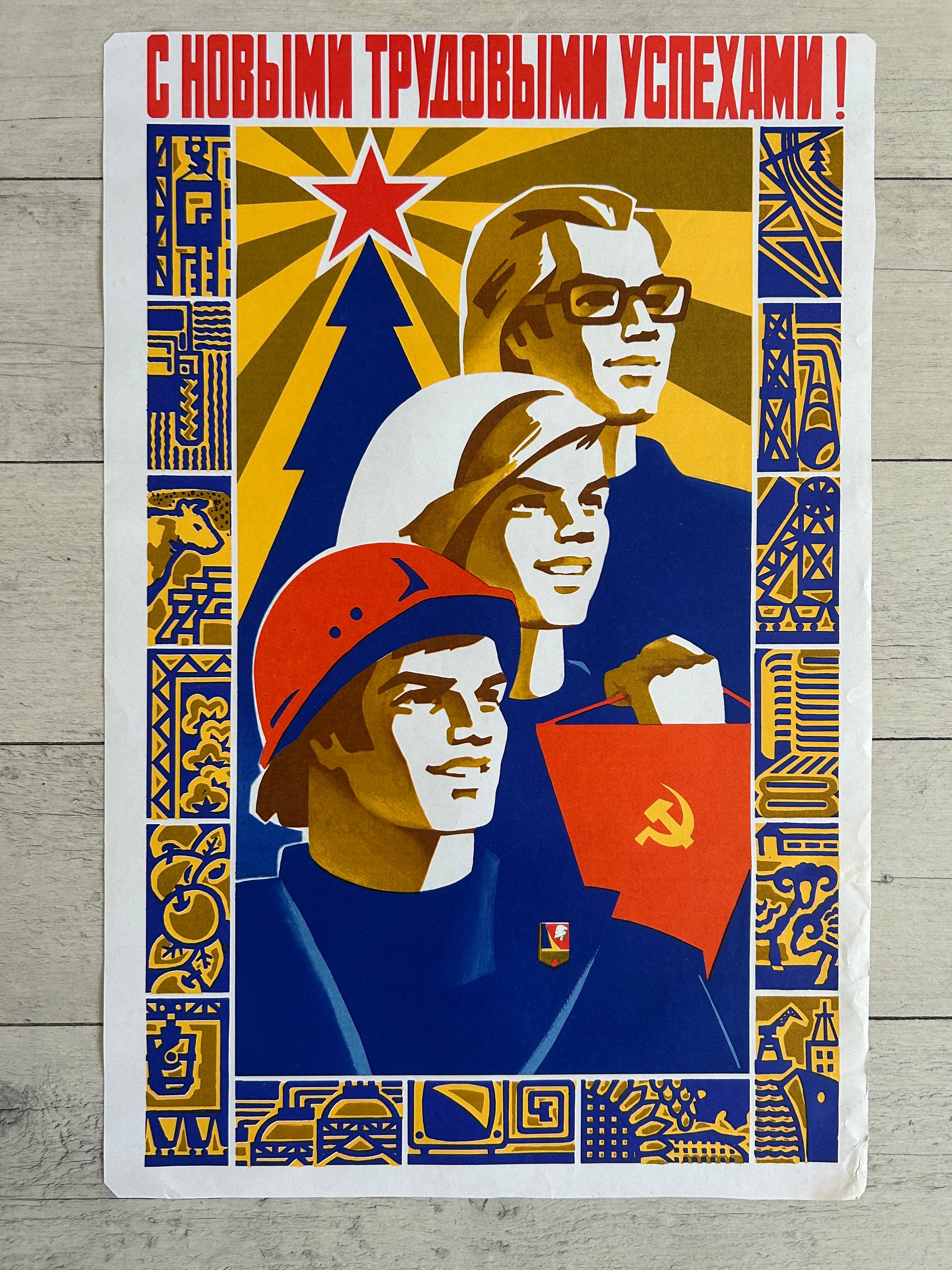 A vintage Soviet propaganda poster print featuring three workers with red stars, hats, and flags, bordered by blue and gold patterns, displayed on a light gray wood background.