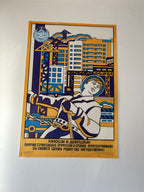 A framed Soviet-style poster mounted on a white wall, featuring a stylized construction worker in a space suit with Russian text and blue, yellow, and white graphic elements.