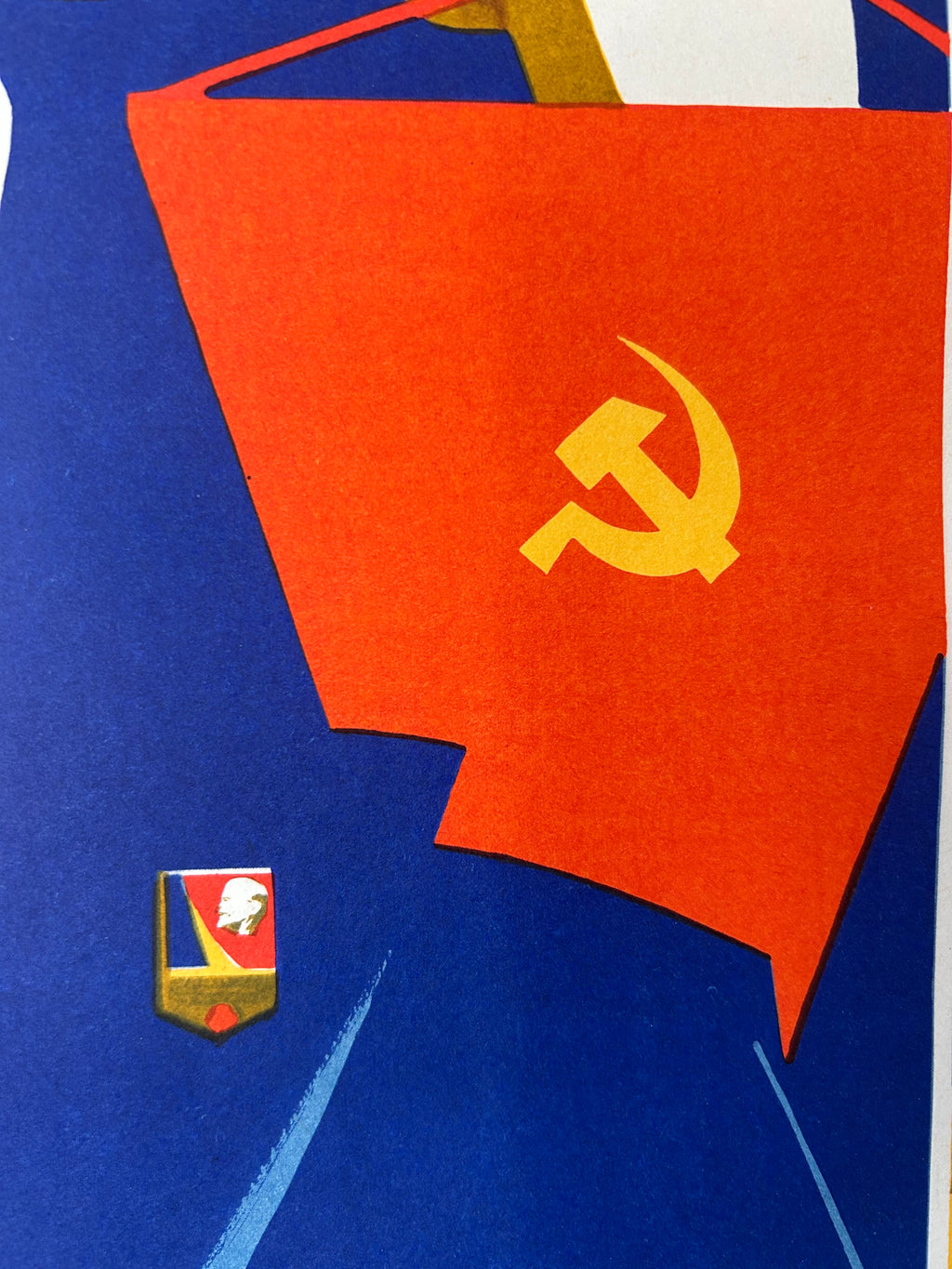 A close-up of a Soviet flag with a yellow hammer and sickle emblem, shown against a blue background with a small Soviet pin badge.
