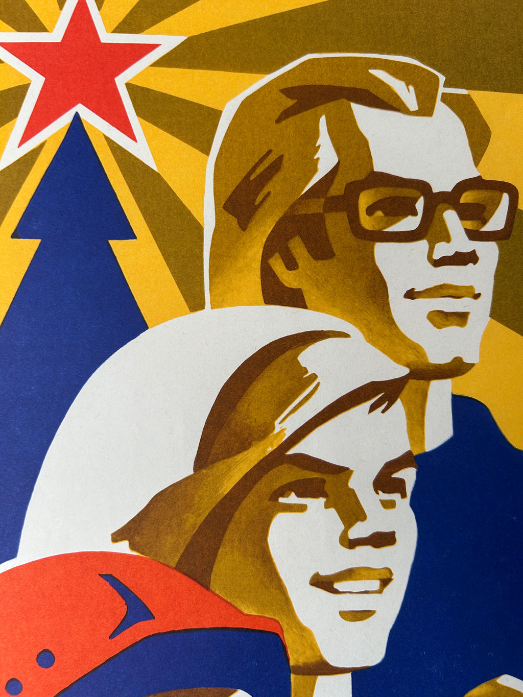A stylized graphic print featuring two illustrated faces in a retro poster style, with bold geometric shapes and a red star on a yellow background.