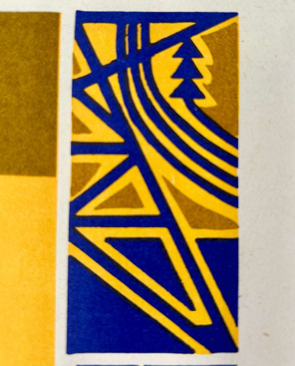 A close-up of an abstract geometric print featuring bold blue and mustard yellow shapes with a stylized tree motif, bordered by off-white margins.