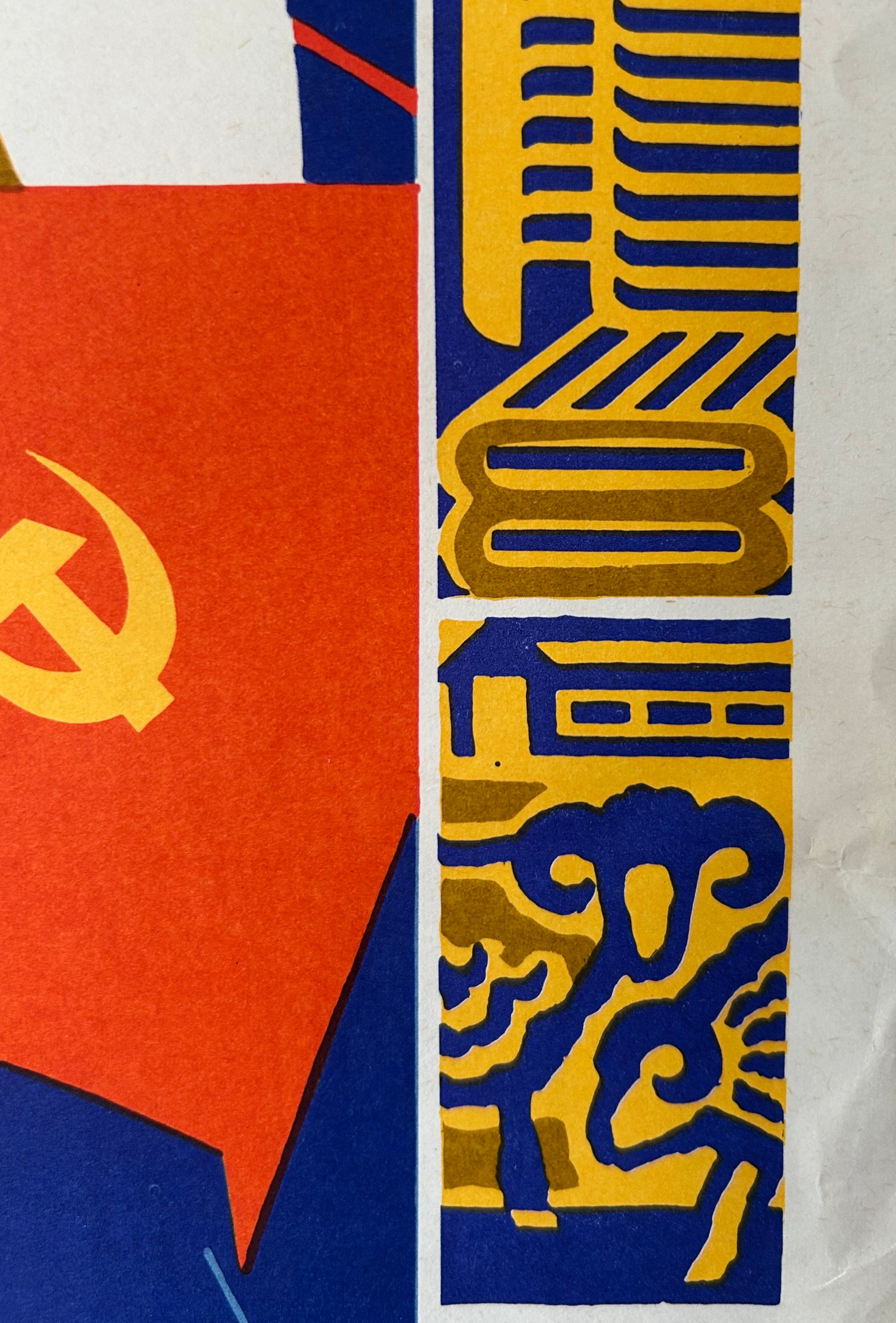 A close-up of a graphic print or poster featuring a red field with a yellow hammer and sickle symbol on the left, and a vertical column of blue and yellow geometric and decorative motifs on the right.