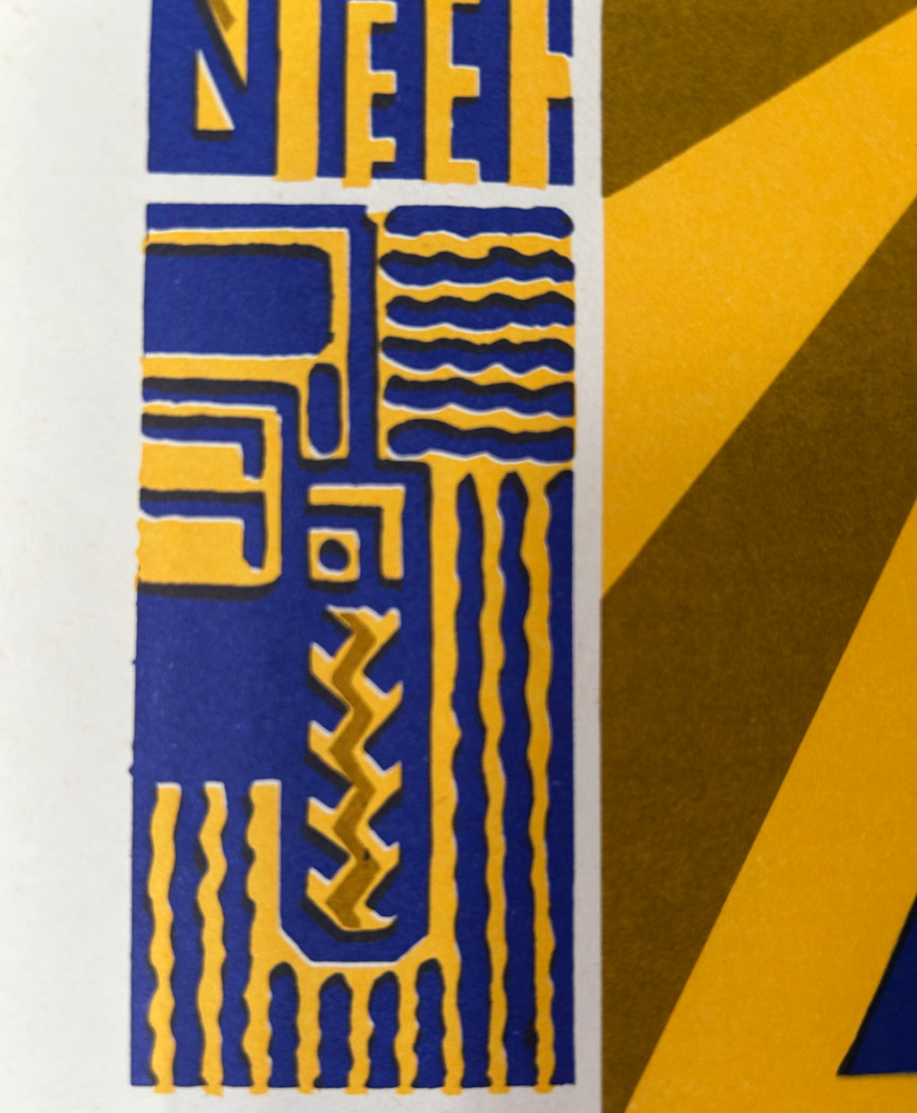 A close-up of an abstract art print featuring geometric shapes and wavy lines in deep blue and golden yellow, with a white border visible on the left.