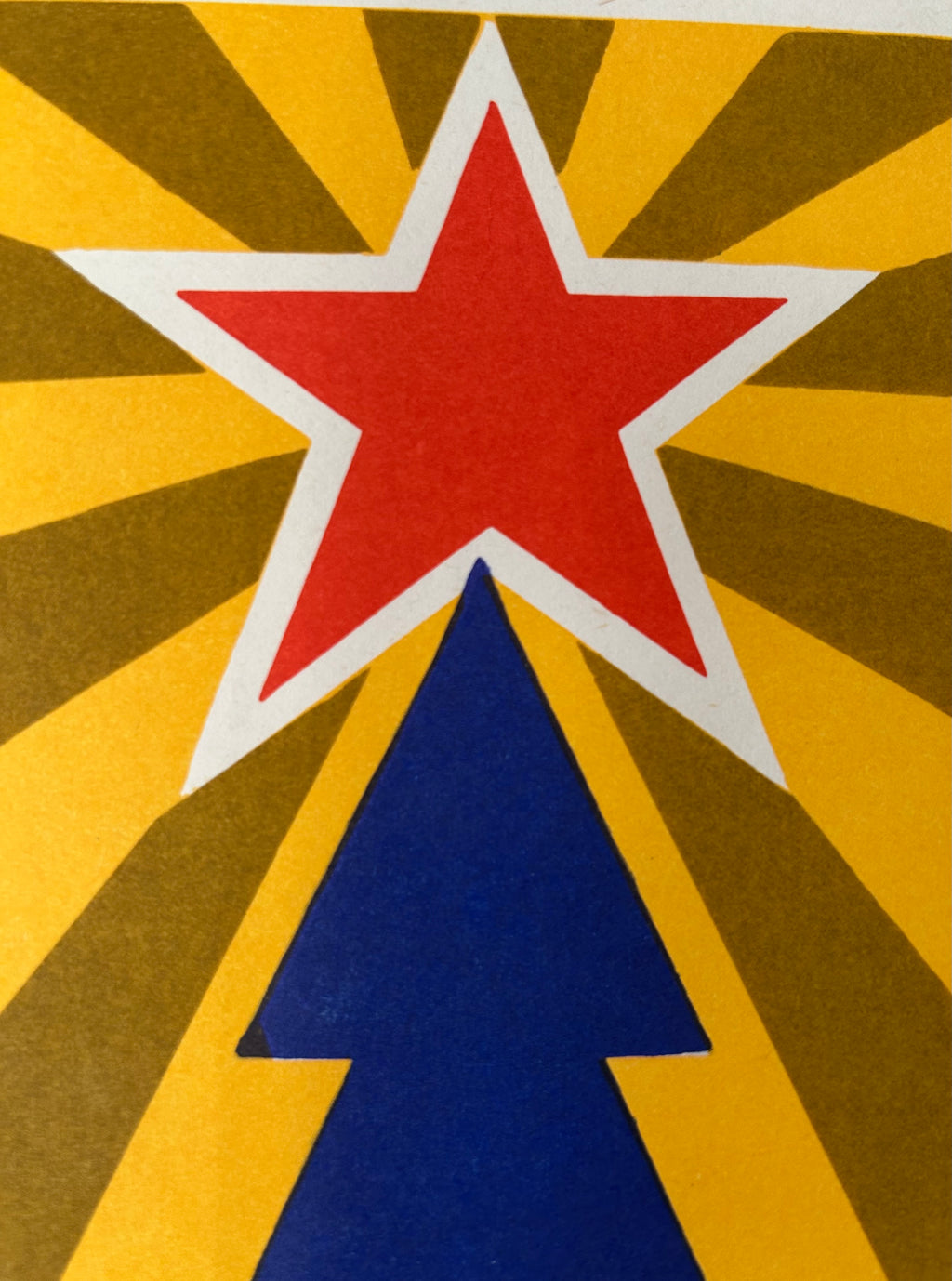 A close-up of a graphic design featuring a red five-pointed star outlined in white, set against a yellow and brown sunburst background with a blue upward-pointing triangle below.