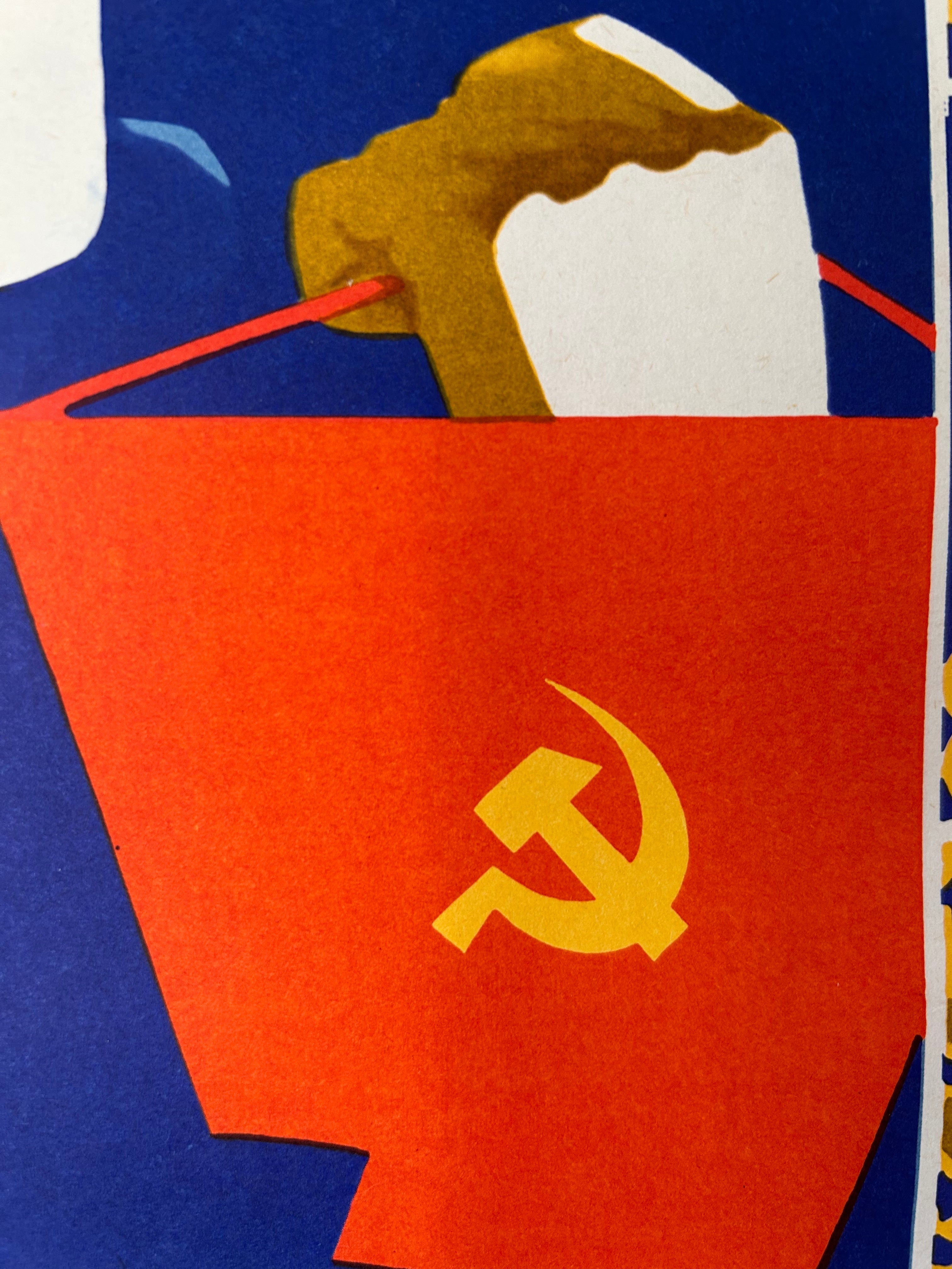 A close-up of a Soviet hammer and sickle symbol printed on a red paper bag or envelope, with a brown and white paper airplane sticking out from the top against a blue background.